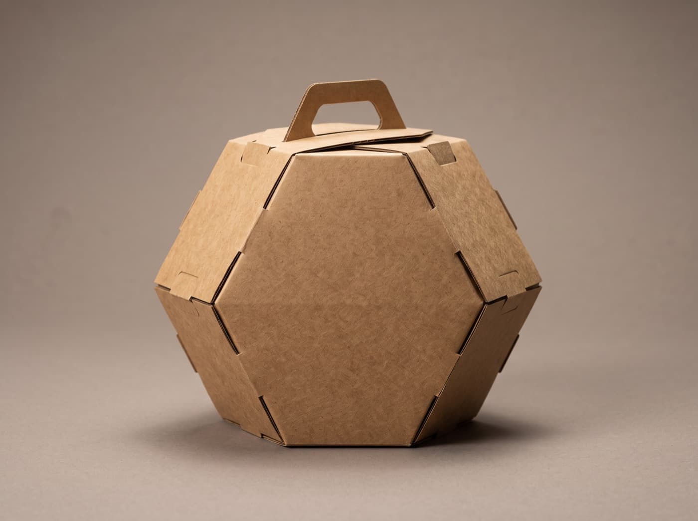 A hexagonal kraft die-cut box with a cut-out carry handle, showing its engineered fold lines.